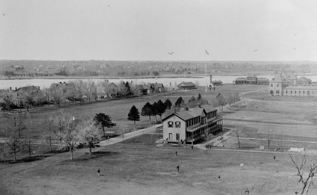 <p>Buildings and trees lined the Parade Ground (left center), located in the middle of Davids Island. View north-northwest, ca. 1889.</p>
