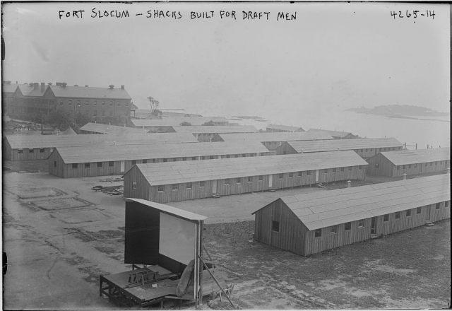 <p>Temporary barracks and an outdoor movie screen were built on the drill field during the First World War to accommodate the crush of recruits passing through Fort Slocum. View to northeast, ca. 1918 (Library of Congress, Prints &amp; Photos Div, GG Bain digital collection).</p>