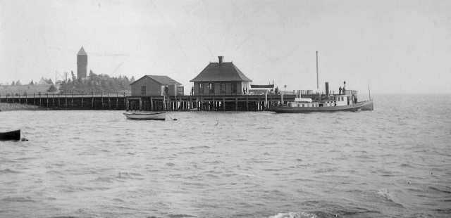<p>Passenger Dock with boathouse (left) and baggage room (right), which were removed in 1938. The Hamilton, an Army tugboat, is moored to the pier. View southeast, ca. 1893.</p>