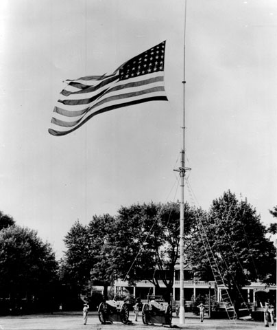 <p>Raising the flag on Fort Slocum&#39;s flagpole, looking north, July 1955. This guyed flagpole was replaced in ca. 1960 by a freestanding monopole.</p>