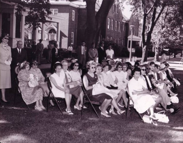 <p>A group watching a ceremony from in front of Building 10 on Officers&#39; Row, view north, July 1964.</p>