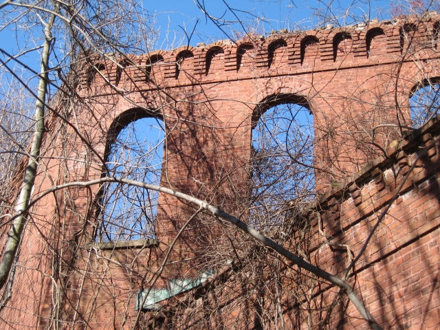 <p><strong>Romanesque Revival, detail</strong>: Round arch window openings and two styles of brickwork cornices. Tower and east wing of Barracks (Building 69), view northwest, January 2007.</p>