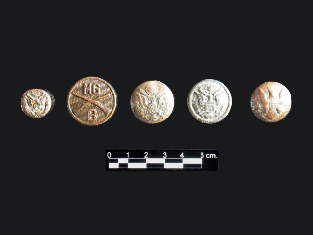 <p>Examples of military uniform buttons found during the 2005-2006 archeological survey of Davids Island. This group includes (left to right) a small sleeve button; a First World War machine gun company collar button; and three blouse, jacket or pocket buttons, including one dating to the Civil War (far right).</p>