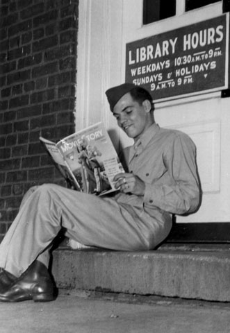 <p>Publicity photograph taken during the Second World War of a soldier sitting on the step of Fort Slocum&#39;s library, then located in Building 69, reading a movie fan magazine.</p>